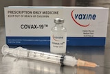 A syringe in front of a box of a trial coronavirus vaccine.