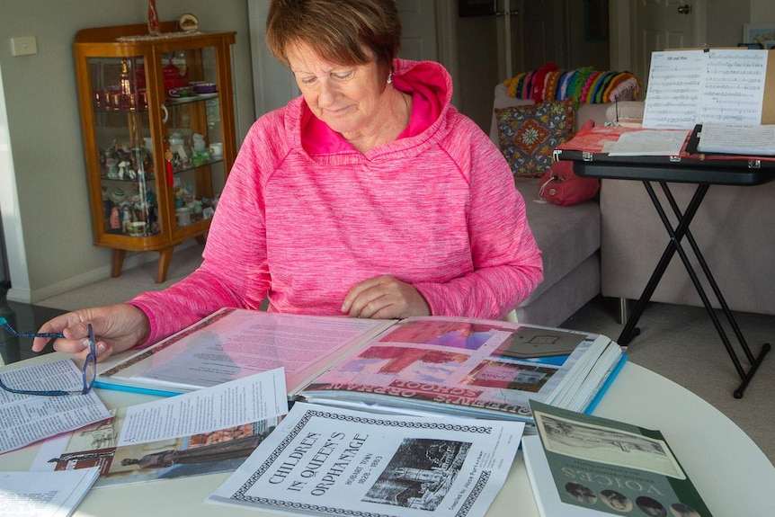 A woman looks over books and photos at her dining table