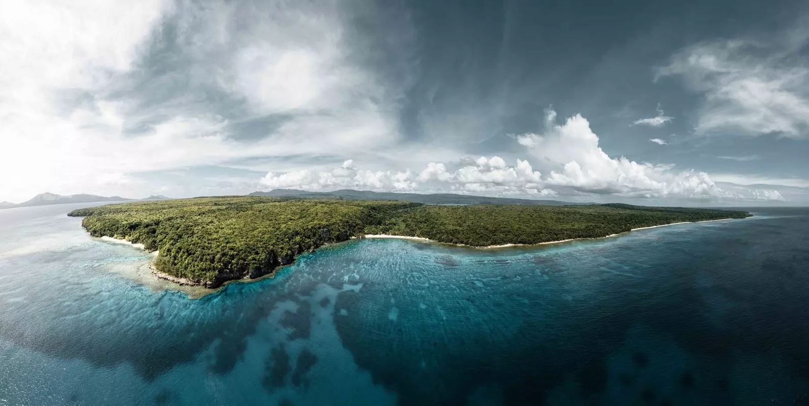 An aerial view of a low-lying island in dark blue water.