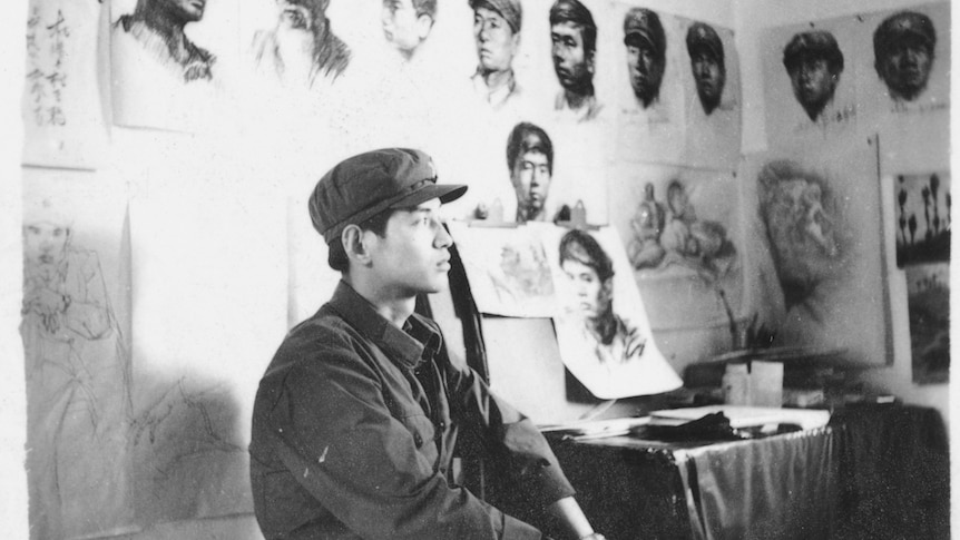 A black-white photo of a young Chinese PLA soldier sitting in a studio.