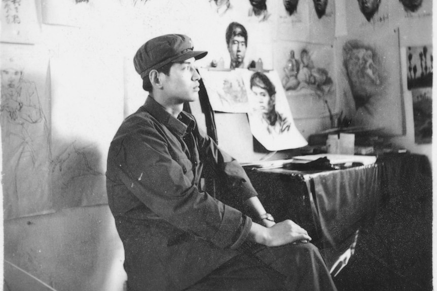A black-white photo of a young Chinese PLA soldier sitting in a studio.