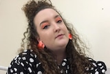 Bethany Cordwell wearing orange earings and orange makeup.