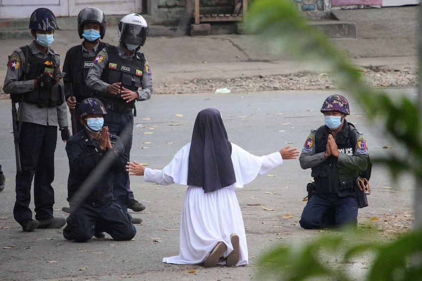 A nun pleads with police not to shoot, with several officers kneeling with hands pressed together