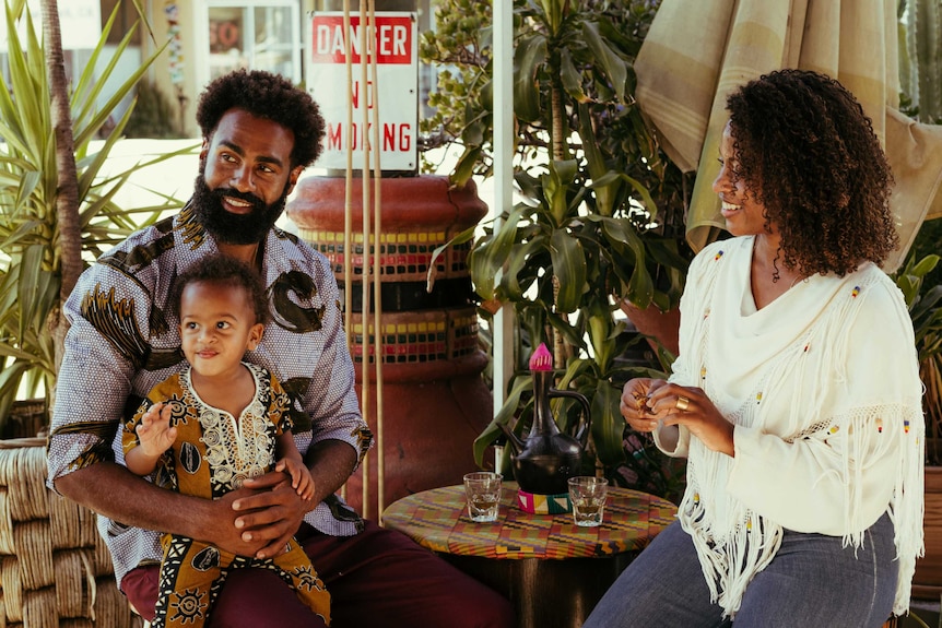 A man, woman and child sit around a small table at a cafe.