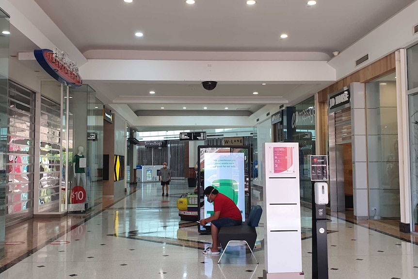 A man sits on a chair in a deserted shopping centre