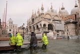 Workers prepare a catwalk so people can walk over a flooded Saint Mark Square, Venice.