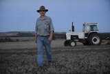 WA Landcare Network chair, Keith Bradby standing in a paddock with a tractor behind him