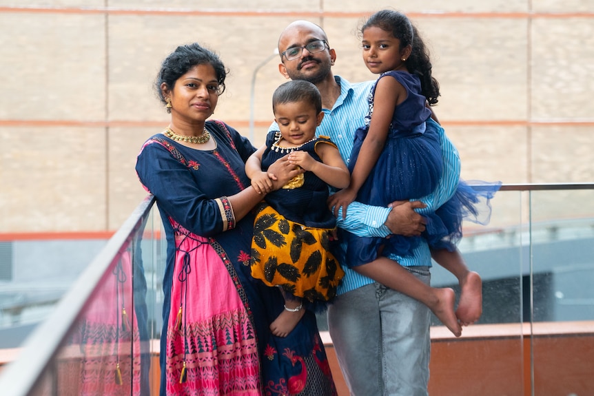 A portrait of a woman and man holding two young girls. 