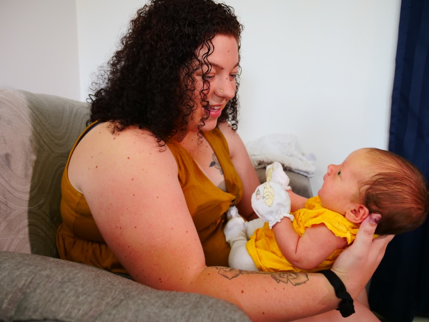 A woman holds her playful baby.