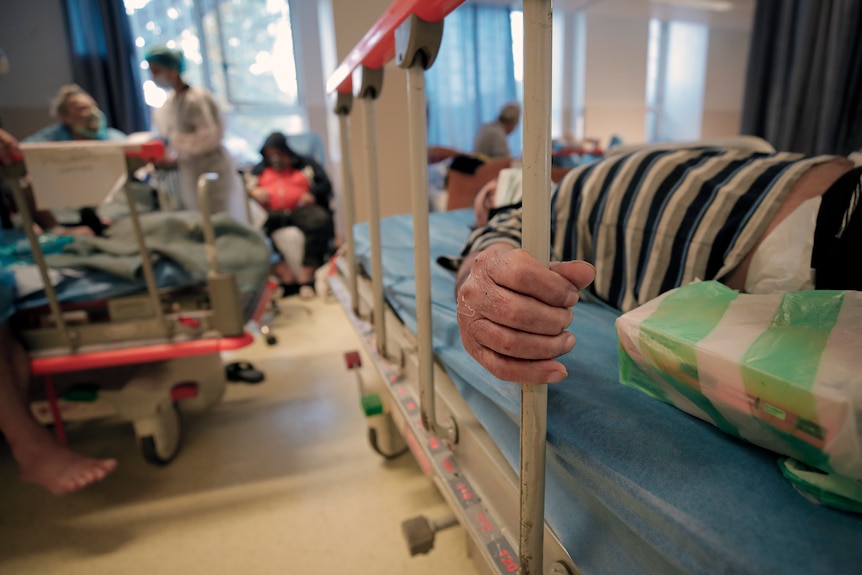 Mâna pacientului este văzută în timp ce pacientul stă întins pe patul de spital