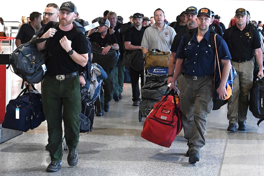 A group of men walks through a Melbourne airport terminal, carrying luggage.