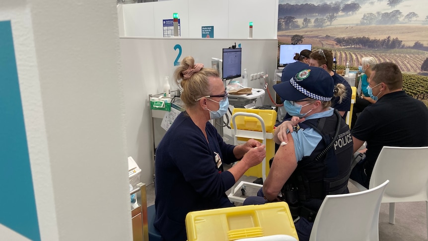 A staff member from Hunter New England Health delivers the COVID vaccine to a police officer