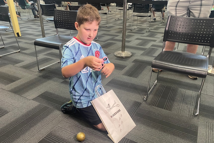 A boy on the ground playing with a fidget spinner