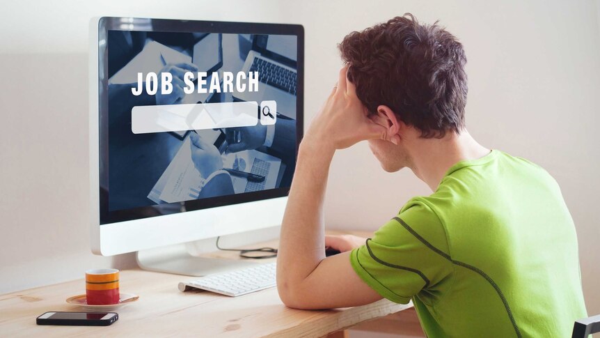Guy sitting at a desk in front of a screen that says job search