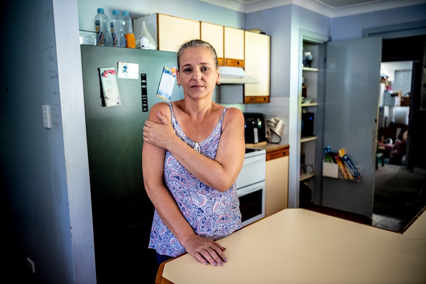 A woman in a kitchen staring down the barrel of a camera