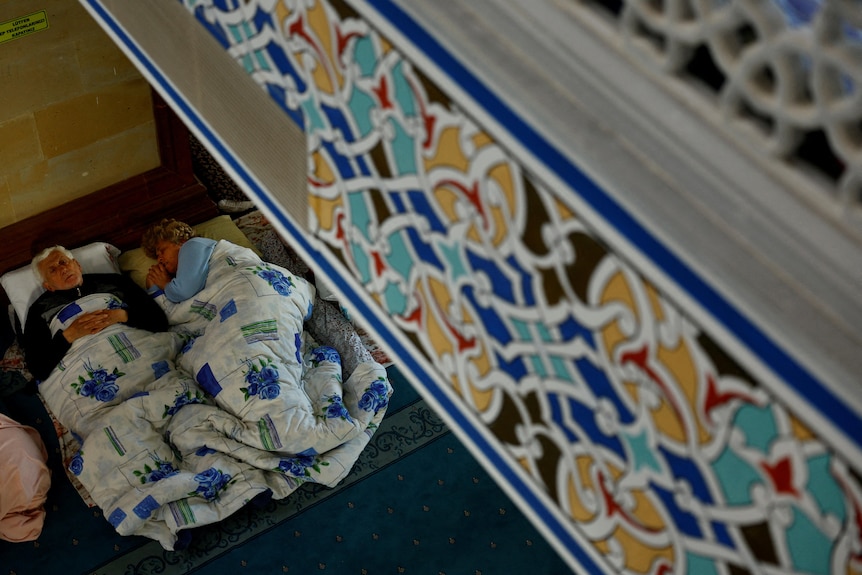 A view from abover which shows a man and woman sleeping on the floor below. 