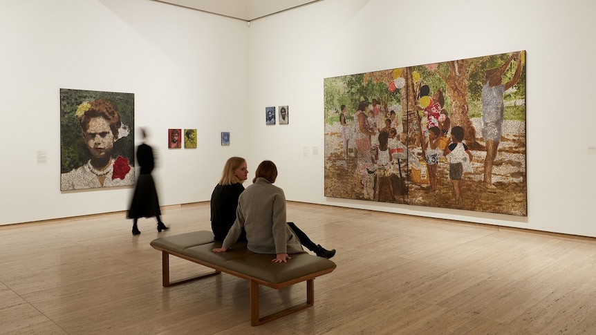 Two people look at Daniel Boyd painting installed at Art Gallery of NSW