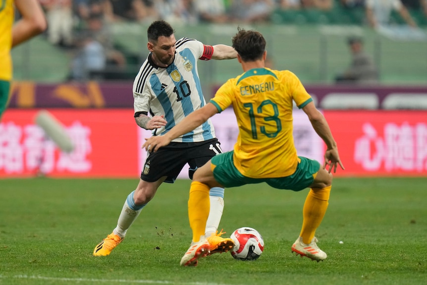 Argentina's Lionel Messi, left, battles for the ball against Australia's Dennis Genreau  during a soccer match. 