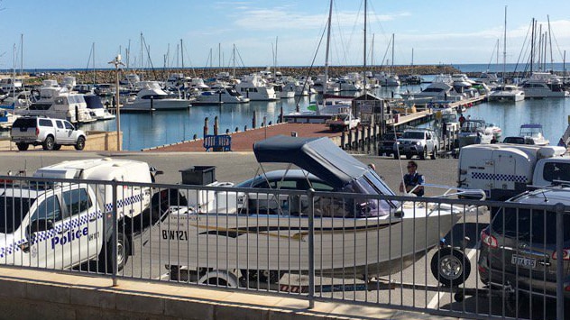A small boat on a trailer at Mindarie Marina with police cars either side.