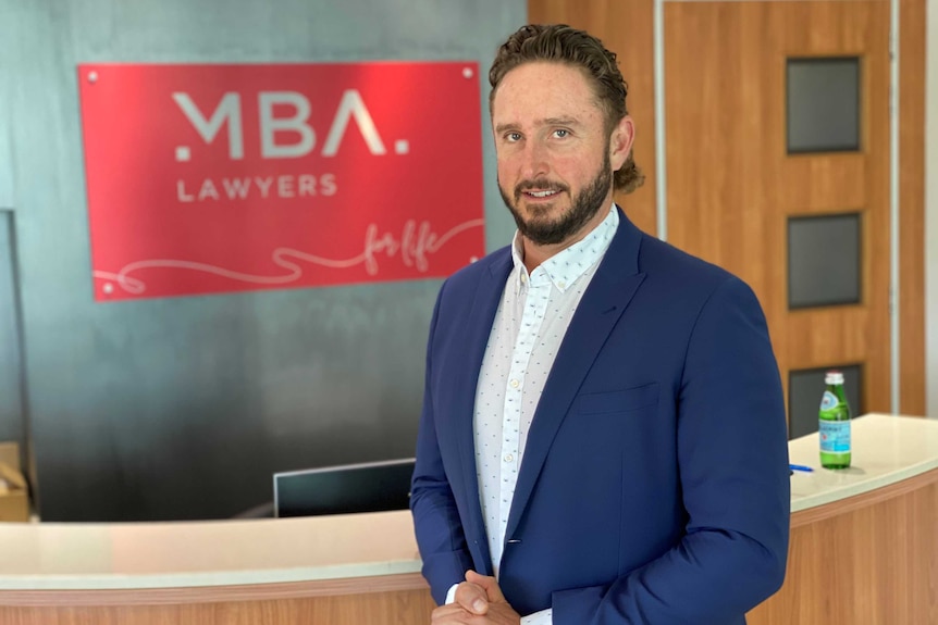 Photo of man in a suit in front of MBA Lawyers sign.
