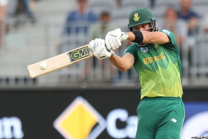 A batsman hits a white cricket ball