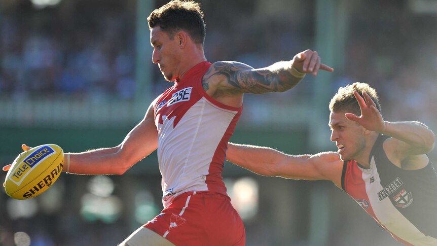 The Sydney Swans' Jesse White holds off the tackle of St Kilda's Sam Fisher at the SCG.