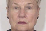 a close-up passport-style photo of a 78-year-old woman wearing dark coloured stud earrings