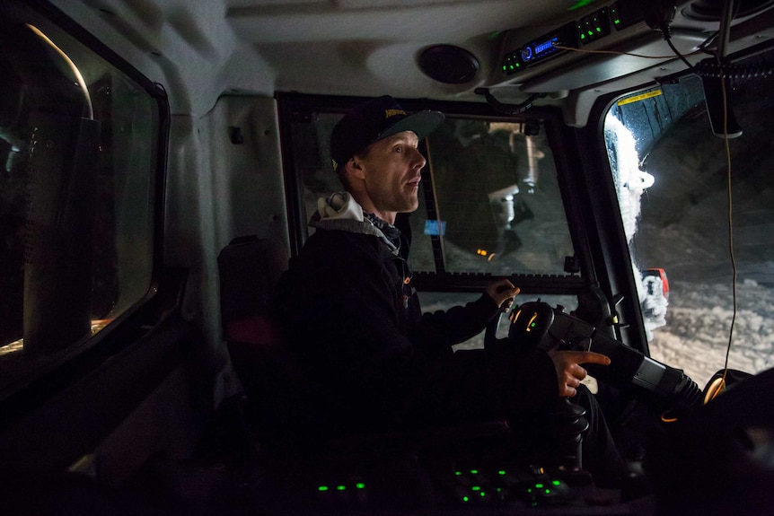 A controller drives inside the cab of a snow grooming machine.