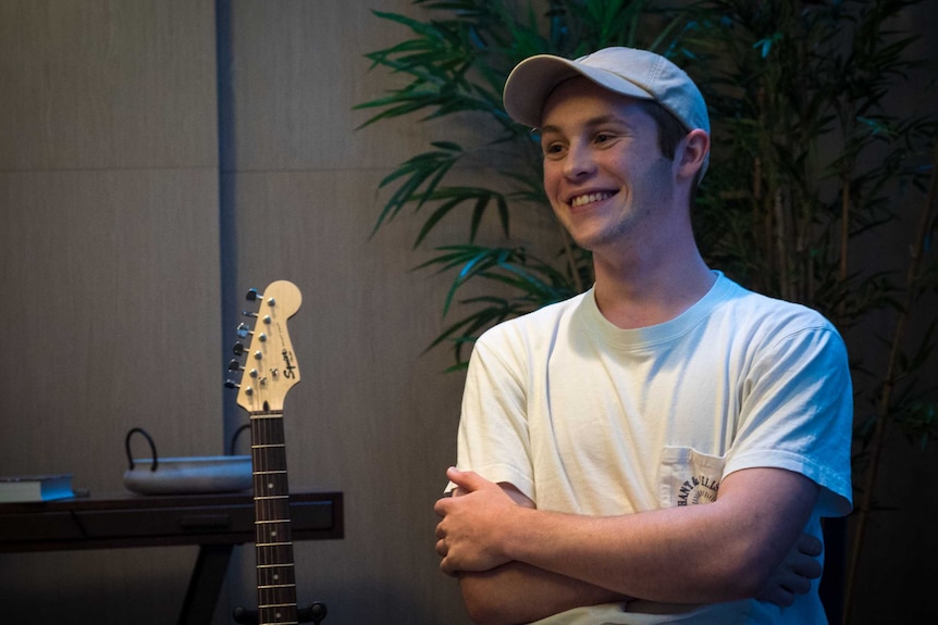 James Robison smiling while sitting beside his guitar