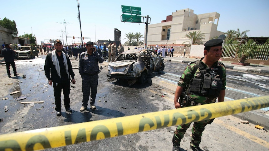 Iraqi security forces and emergency personnel gather a the site of a suicide attack.