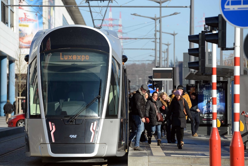 People disembark from a tram.