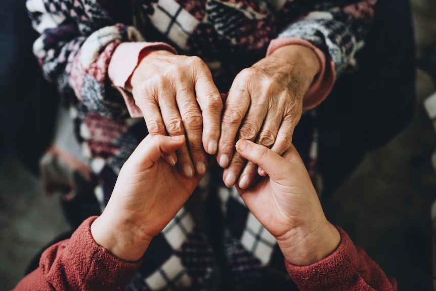 A young woman and a senior woman, grandmother and granddaughter, holding hands