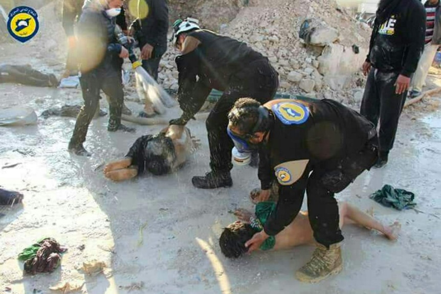 Rescue workers hose down children hit by the gas attack.