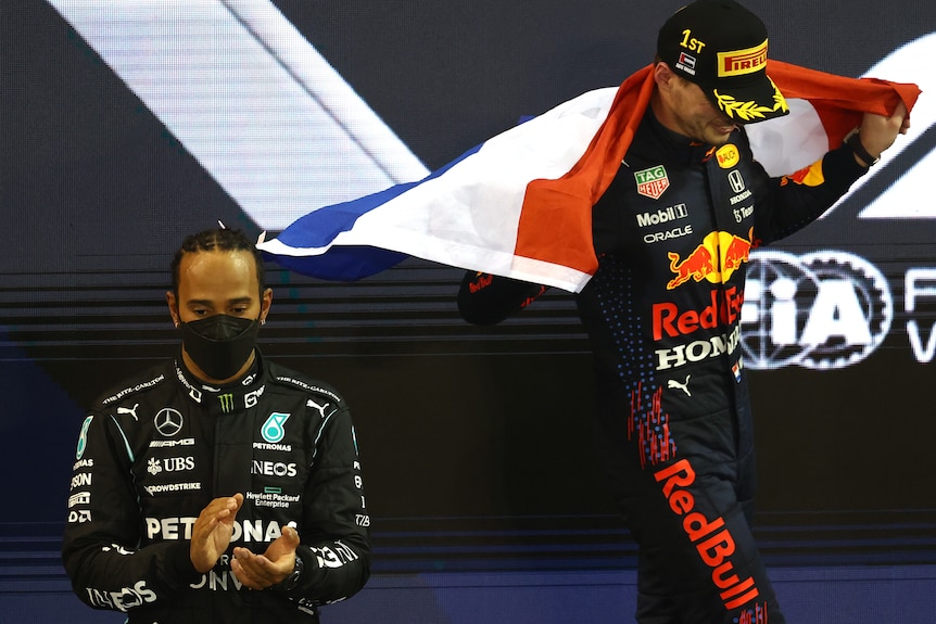 Hamilton applauds as Verstappen hoists the Dutch flag in triumph.