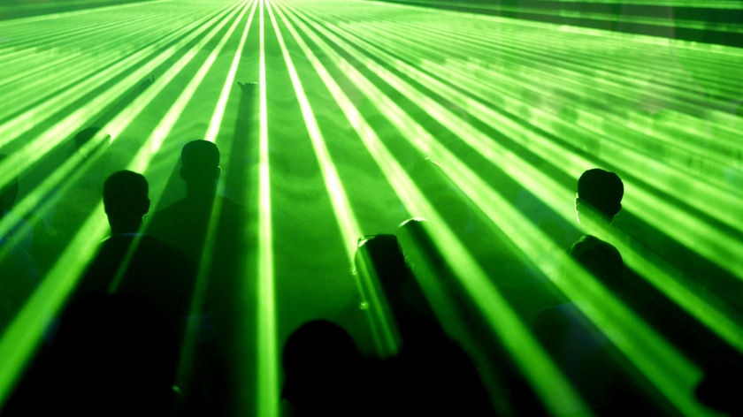 Arty shot of revellers at a rave party, with their heads poking through a green laser show