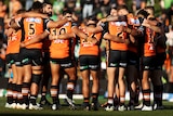 A group of rugby league players huddle up before a game.