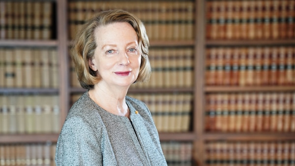Portrait of a woman in her late sixties who is in front of a book case. She has short hair and light blue eyes.