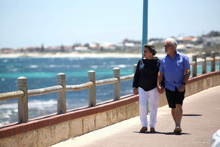 Steve and Wendy walk along a pier, looking out at the ocean.