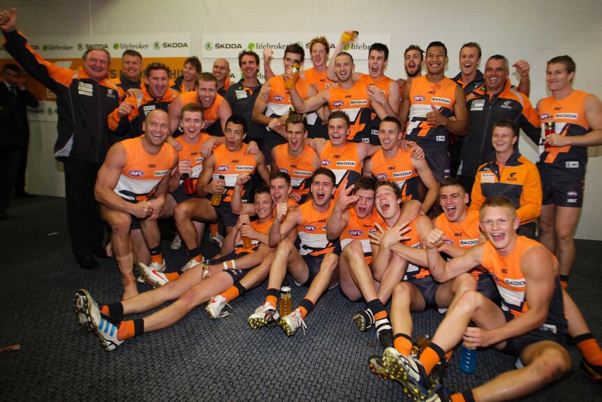 Australian rules football players celebrate their club's inaugural win.