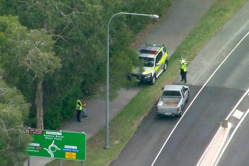 A police car and a ute are parked on the side of the road.