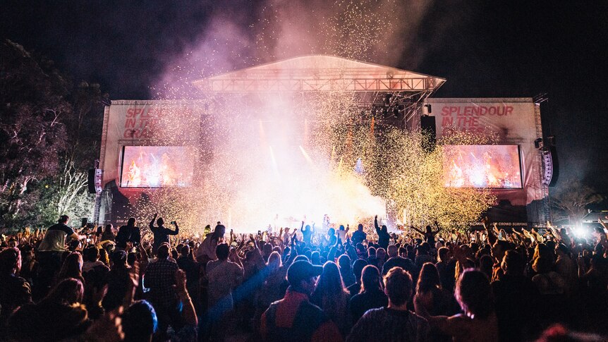 A Splendour In The Grass stage at night with bright lights and confetti above a packed crowd.