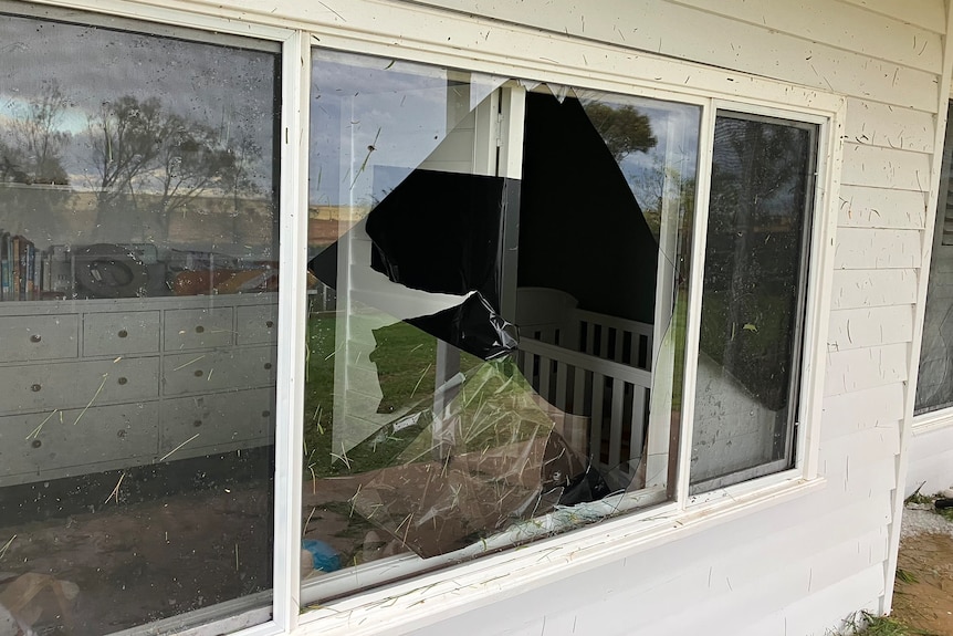 Smashed windows of a house with white walls.