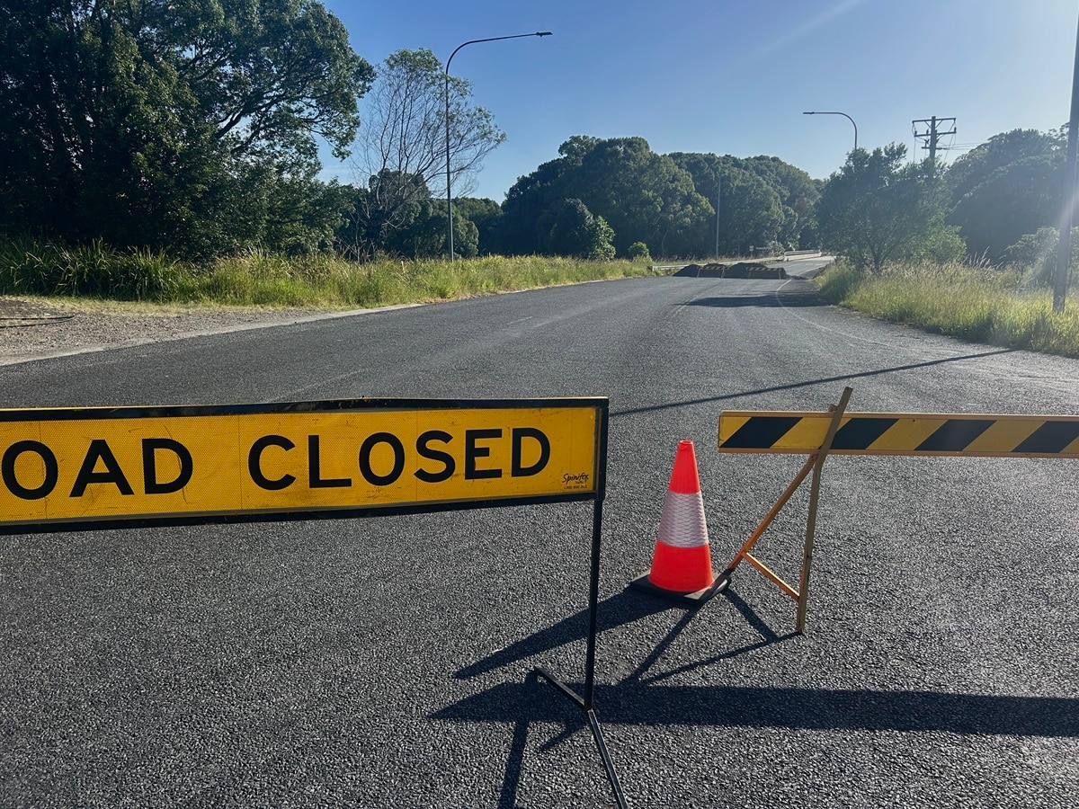 Una señal de cierre de carretera bloquea un camino rural.
