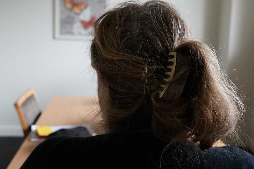 The back of a woman's head, sitting alone in a room