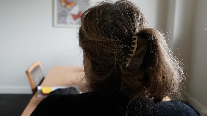 The back of a woman's head, sitting alone in a room