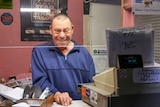 A man in a blue windcheater stands at the ticket counter of a cinema.