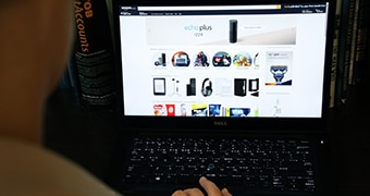 A woman online shopping on a black laptop.