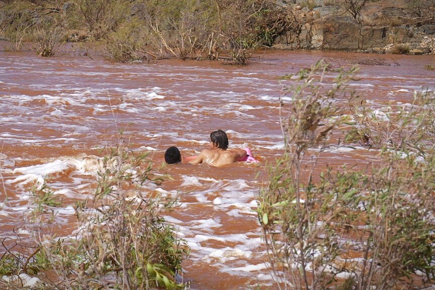 Children swimming in a brown outback river