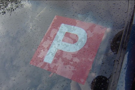 Picture of a car windscreen with a p-plate on it.