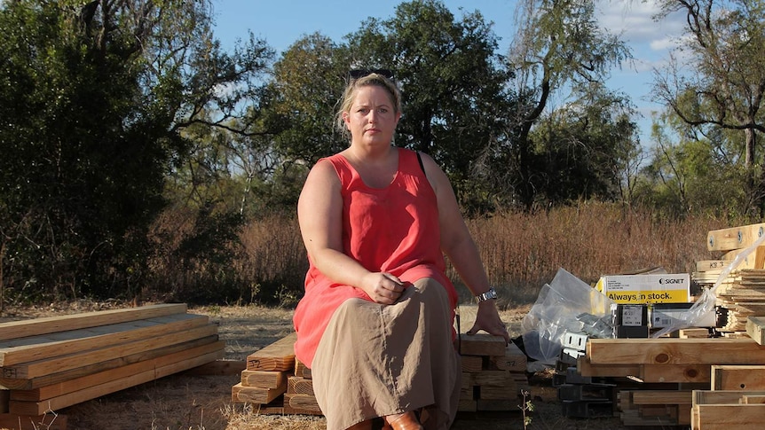 A photo of Kelly Wright sitting on some planks of wood in the afternoon sunlight.